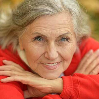 ældre kvinde i rød strikbluse ser glad og lykkelig ud