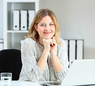voksen kvinde smiler glad fra sit skrivebord