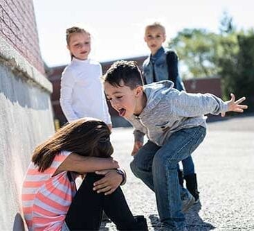 pige krummer sammen i gråd da en dreng driller i skolegården