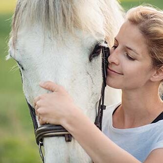 ung kvinde med hånd og ansigt på hvid hest