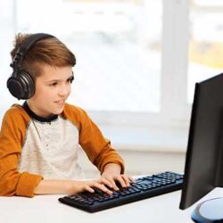 en dreng sidder koncentreret foran computer og med høretelefoner på