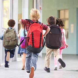 6 elever med skoletasker på ryggen løber på en skolegang