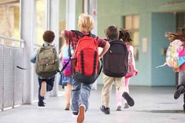 6 elever med skoletasker på ryggen løber på en skolegang